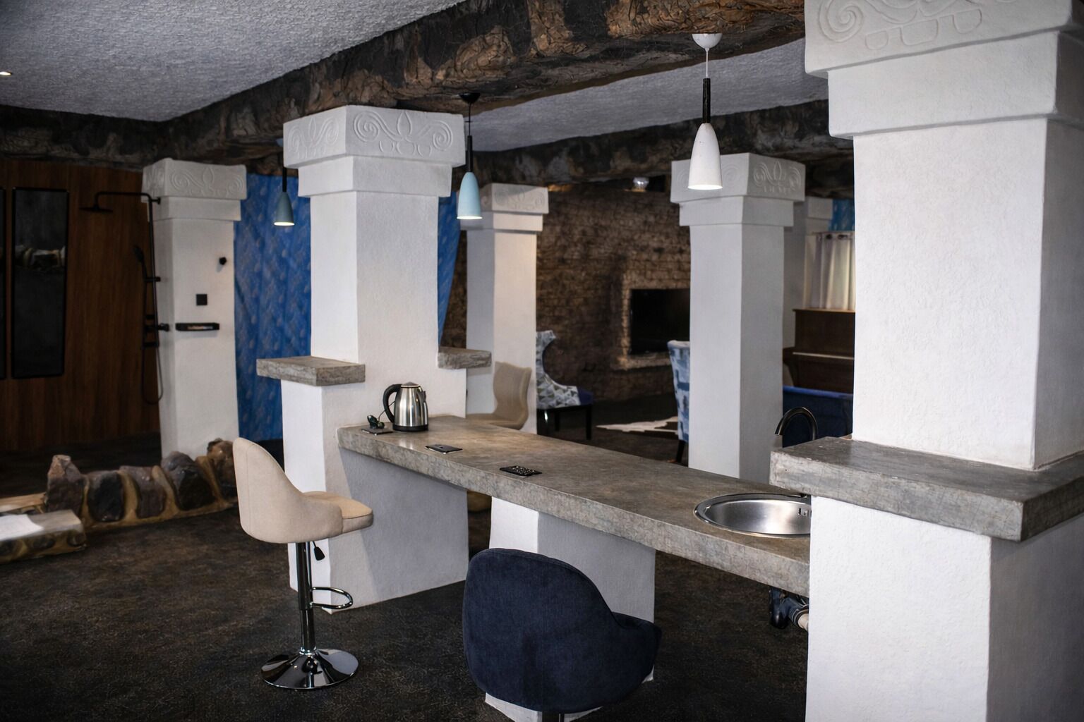 Una cocina moderna con barra, destacando un mostrador de piedra, taburetes de bar e iluminación colgante.