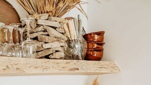 A kitchen shelf with glassware, wooden utensils, and a copper mug. - Maison de Vacance en Lisière de Forêt (Labenne)