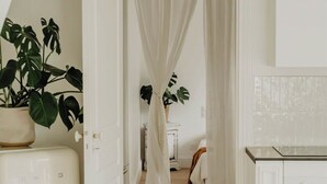 A room with a white cabinet, a plant, and a white door leading to another room. - Maison de Vacance en Lisière de Forêt (Labenne)