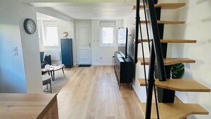 Un amplio espacio habitable con una escalera de madera, una mesa de comedor y un sofá.
