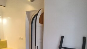 A bathroom with a yellow sink, a white door, and a black ladder leaning against the wall. - Villa Mogador Essaoura (Essaouira)