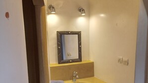A bathroom with a yellow sink, a mirror, and two wall-mounted lights. - Villa Mogador Essaoura (Essaouira)