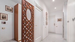 Un couloir aux murs blancs, orné de tableaux encadrés et d’un panneau décoratif en bois.