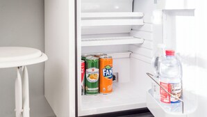 Un réfrigérateur contenant trois canettes de soda et une bouteille d’eau.