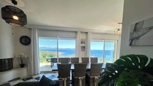 A living room with a large window, a dining area with chairs, a black and white checkered floor, and a large green plant. - Top of Villa sea view,  heated swimming pool (Roquebrune-sur-Argens)