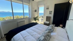 A bedroom with a large bed, a view of the sea, and a balcony with a chair. - Top of Villa sea view,  heated swimming pool (Roquebrune-sur-Argens)