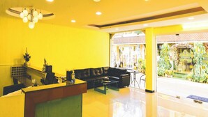 A reception area with a black leather sofa, a reception desk, and a chandelier. - Siamese Serenity Stays (Pattaya)