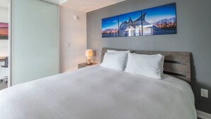 Un cuarto de hotel con una cama grande, una mesita de noche con una lámpara y un cuadro en la pared.