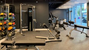 Un gimnasio con equipo de ejercicio, un espejo y un estante con balones medicinales.