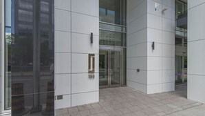 Entrada moderna de un edificio con puerta de vidrio, el número '199' en la pared y piso de baldosas.