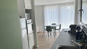 A modern kitchen with a built-in oven, a sink, and a dining area with chairs and a table. - Little House built in 2024 and very comfortable. Near Annecy (Cuvat)