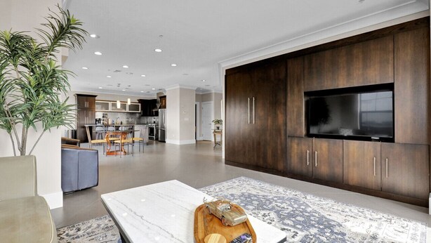 Una sala de estar moderna con un televisor de pantalla plana grande, muebles de madera oscura, una mesa de centro de mármol y un tapete estampado.