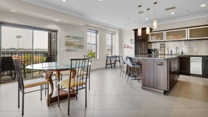 Una cocina moderna con una isla grande, taburetes de bar y un comedor con mesa de vidrio y sillas.
