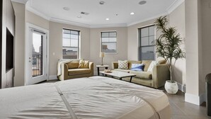 Habitación de hotel con una cama grande, dos sofás, una mesita de centro y una planta en maceta.