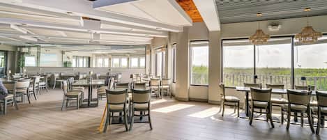A spacious dining area with high ceilings, large windows, and modern furniture.