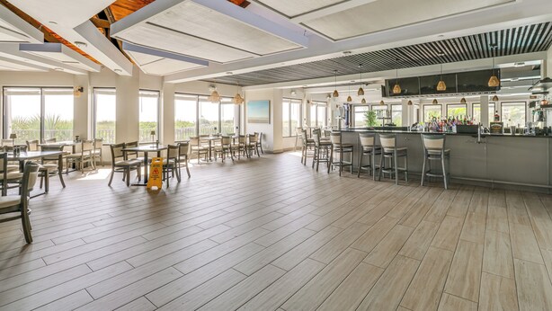 A spacious restaurant with high ceilings, large windows, and a bar area. - Luxe Fort Pierce Beach Condo w/ Golf Views! (Fort Pierce)