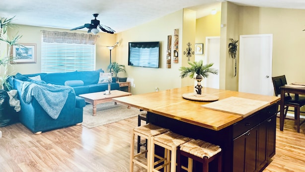 A modern kitchen with a wooden island, a blue sofa, and a dining area with a chair. - The perfect spot for family & friend! Best private getaway in Mohave Valley 🔆 (Mohave Valley)