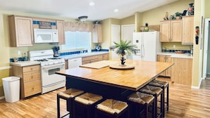 A modern kitchen with wooden cabinets, a central island with bar stools, a stove, and a refrigerator. - The perfect spot for family & friend! Best private getaway in Mohave Valley 🔆 (Mohave Valley)