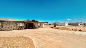 A residential building with a covered patio, a garage, and a well-maintained lawn. - The perfect spot for family & friend! Best private getaway in Mohave Valley 🔆 (Mohave Valley)
