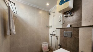 Casa de banho com chuveiro, sanita e porta-toalhas.
