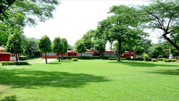 Um gramado bem cuidado com uma área de recepção e um edifício com telhado vermelho.
