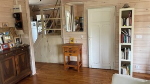 Un interior de madera con piso de madera, una puerta blanca, una estantería y una pequeña mesa de madera.