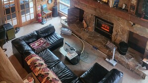 A cozy living room with a stone fireplace, leather sofas, and a variety of wall-mounted animal decorations. - Beautiful Lodge for Weddings, Reunions, Events or Family Gatherings. Sleeps 25+ (Redfield)