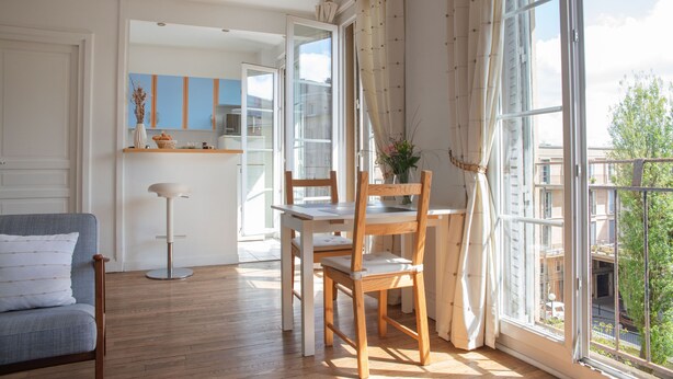 Un salon moderne avec un coin repas, de grandes fenêtres et une vue sur la ville.