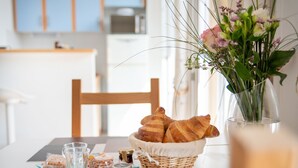 Une table de petit-déjeuner avec des croissants, des pots de miel et un vase de fleurs.