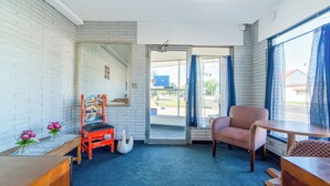 A room with a blue carpet, a wooden chair, a table, a white swan decoration, and a door leading outside. - The Inn by El Dorado Lake (El Dorado)