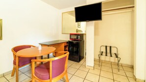 A small room with a wooden table and chairs, a black refrigerator, a microwave, a television mounted on the wall, and a metal chair. - The Inn by El Dorado Lake (El Dorado)