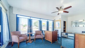 A room with a ceiling fan, two patterned chairs, a small round table, and a wooden cabinet. - The Inn by El Dorado Lake (El Dorado)