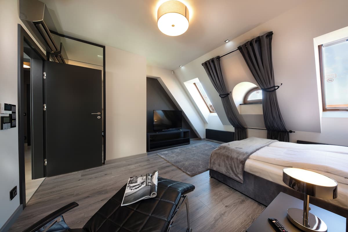 Een moderne hotelkamer met een bed, een televisie, een bureau en een raam met gordijnen.