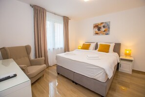 Une chambre d’hôtel avec un lit, une chaise, un bureau et une table de chevet avec une lampe.