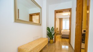 A hallway with a wicker bench, a potted plant, and a bed in the background. - Apartment Riva Parenzo (Porec)