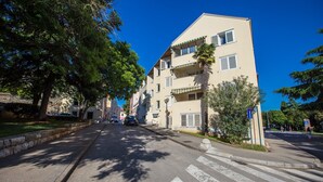 A street with a two-story building, a crosswalk, and a pedestrian. - Apartment Riva Parenzo (Porec)