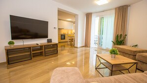 A modern living room with a flat-screen TV, wooden entertainment unit, and a dining area with a kitchen in the background. - Apartment Riva Parenzo (Porec)