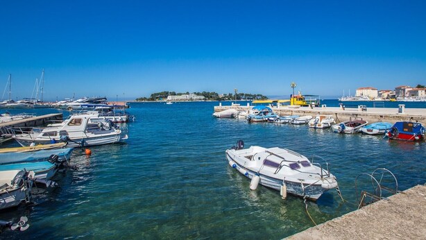 A marina with various boats docked, clear blue water, and buildings in the background. - Apartment Riva Parenzo (Porec)