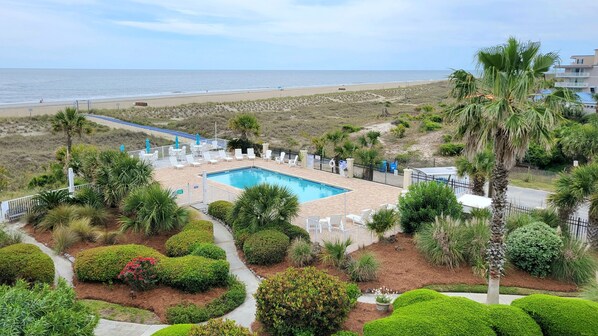 Un espace piscine avec des chaises longues et vue sur la plage.