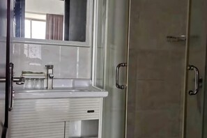 A bathroom with a white sink, a mirror, and a glass shower enclosure. - Xiangzhi Hotel (Yueqing)