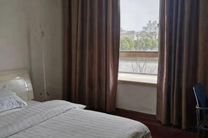 A hotel room with a bed, a window with curtains, and a view of the outside. - Xiangzhi Hotel (Yueqing)