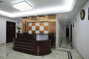 A reception area with a reception desk, a wall-mounted clock, and a potted plant. - Xiangzhi Hotel (Yueqing)
