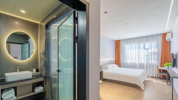 Une chambre d’hôtel moderne dotée d’un grand lit, d’un bureau et d’une salle de bain avec une douche à parois de verre.