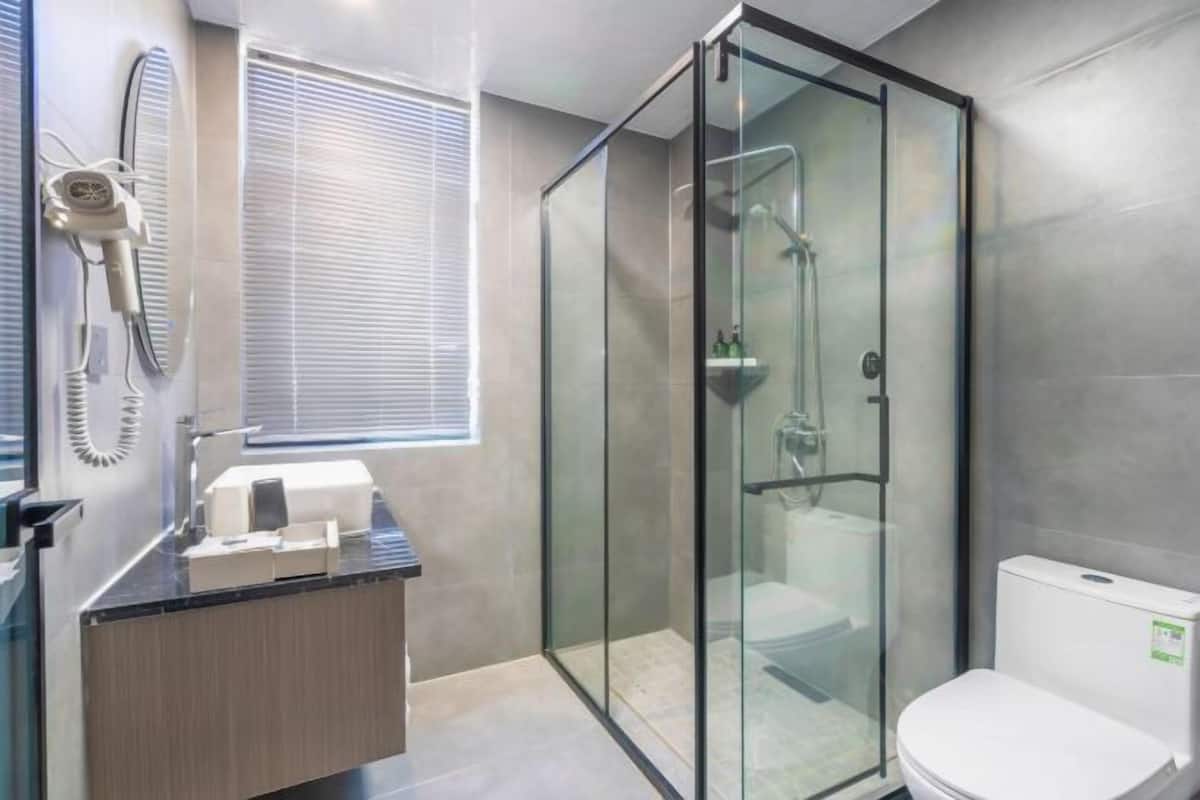 Ein modernes Badezimmer mit einer Duschkabine, einer Toilette und einem Fön auf einer Ablagefläche.