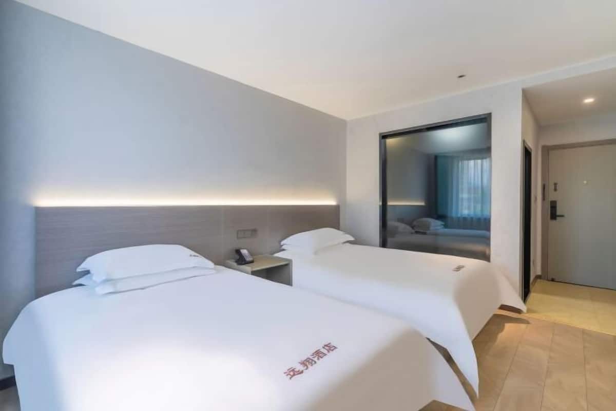 Ein Hotelzimmer mit zwei Betten, einem Nachttisch und einem Spiegel.