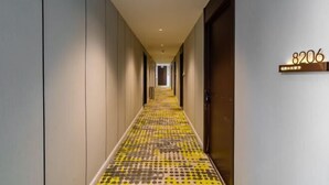 Un couloir d’hôtel avec un sol à motifs, une porte portant le numéro 8206 et une enseigne avec des caractères japonais.