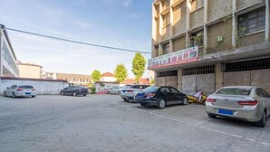 Un parking où plusieurs voitures sont garées devant un immeuble à étages, doté de balcons.