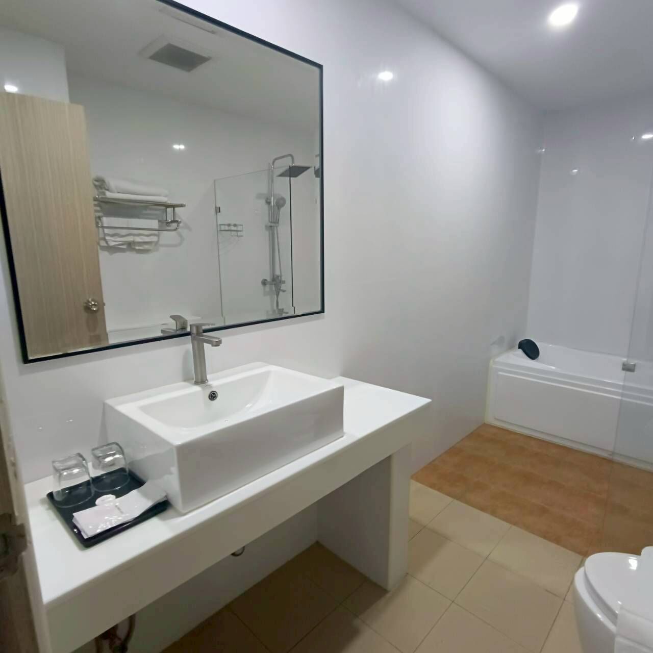 A modern bathroom with a white sink, mirror, and bathtub.