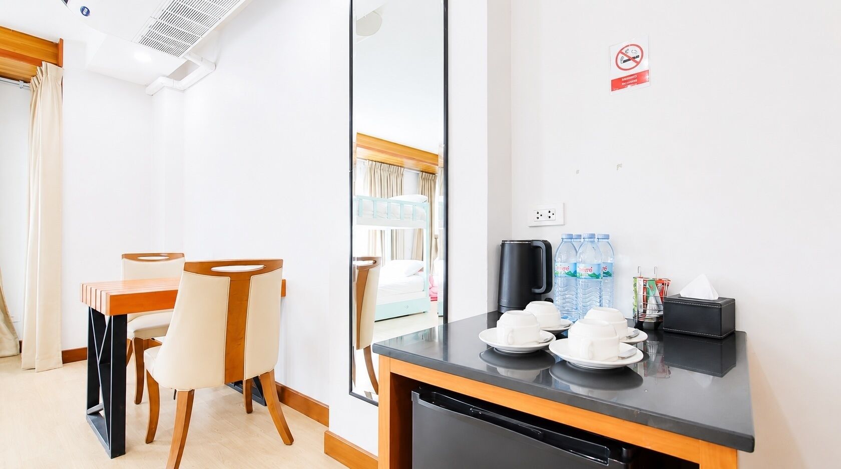 A hotel room with a dining area, a bed, a coffee station, and a view of the outside.