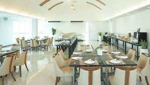 A spacious dining area with multiple tables and chairs, a long counter with a television, and a modern ceiling design. - Cozy Don Mueang Hotel (Bangkok)